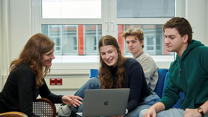 Studierende schauen gemeinsam auf einen Laptop