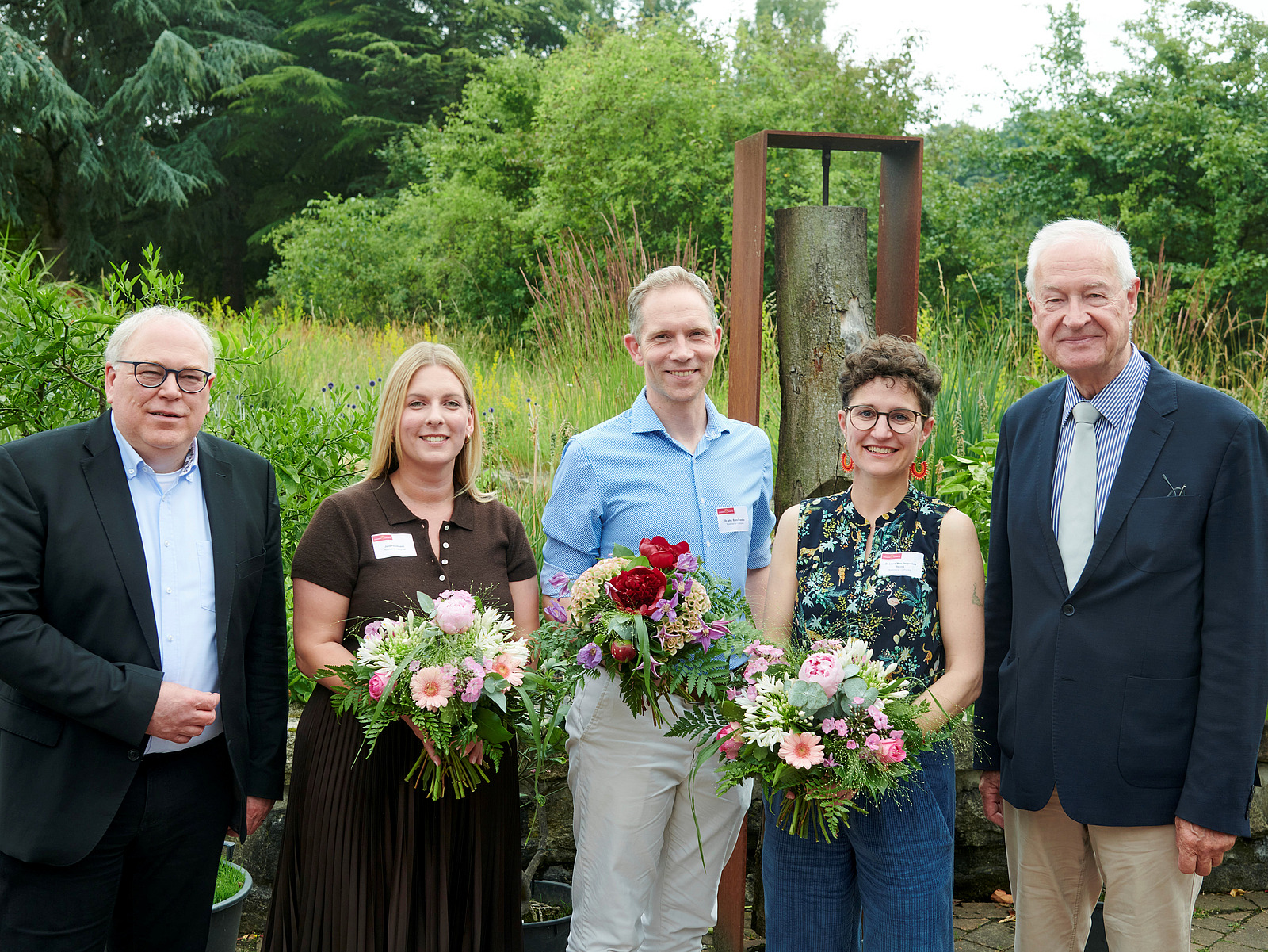 Männer und Frauen blicken in die Kamera.