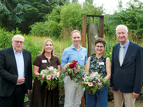 Männer und Frauen blicken in die Kamera.