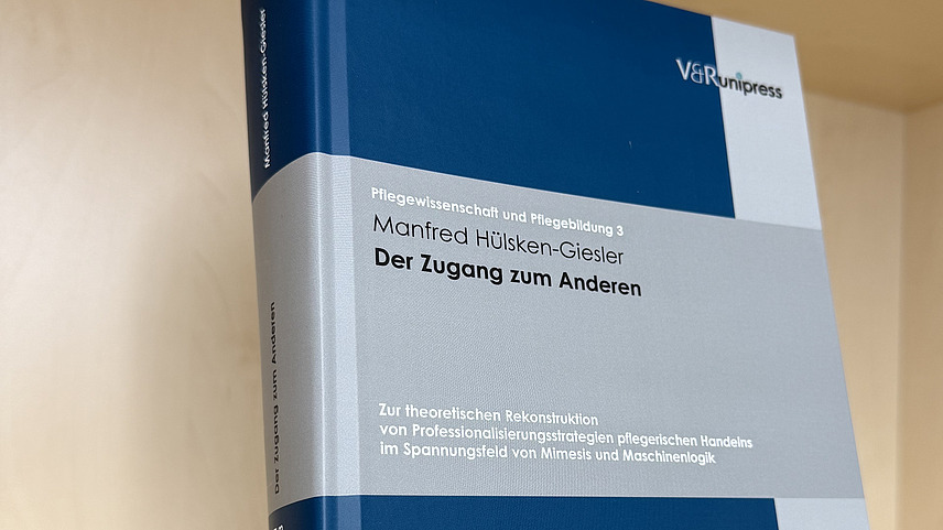 Ein Fachbuch von Manfred H&uuml;lsken-Giesler mit dem Titel "Der Zugang zum Anderen" steht in einem Regal.