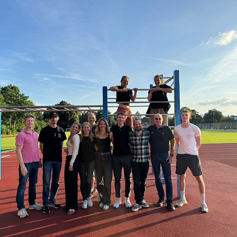 Kollegium des Instituts für Sport- und Bewegungswissenschaften posiert vor der Calisthenics Anlage auf dem Sportplatz.