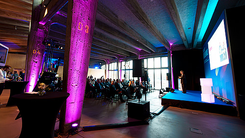View of the audience and stage, illuminated in bright colors