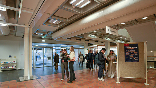 Menschen in einem Raum schauen in Infobroschüren.