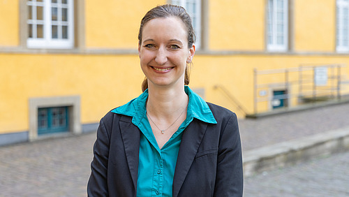 A woman in a black blazer smiles at the camera.