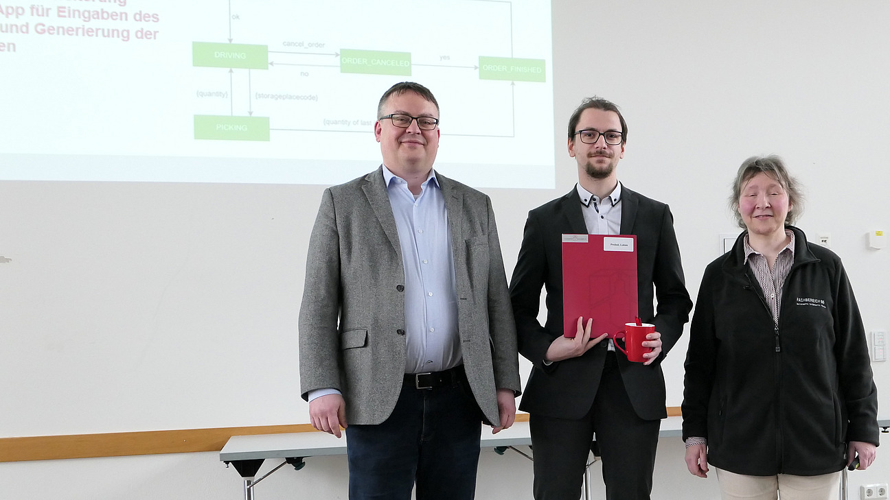 A graduate stands between the dean and the dean of studies.