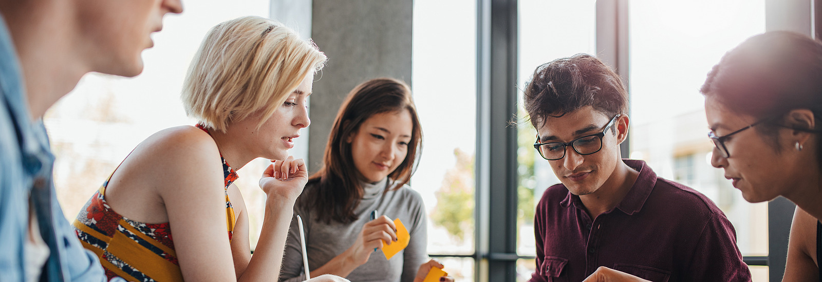 Mehrere Menschen arbeiten gemeinsam an einem Tisch und Brainstormen