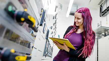 A smiling data center employee notes something from a display on a cabinet in the boiler room.