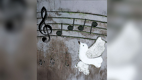 Eine Friedenstaube, eine Notenzeile mit einem Violinschlüssel und einigen Noten sowie japanische Schriftzeichen.