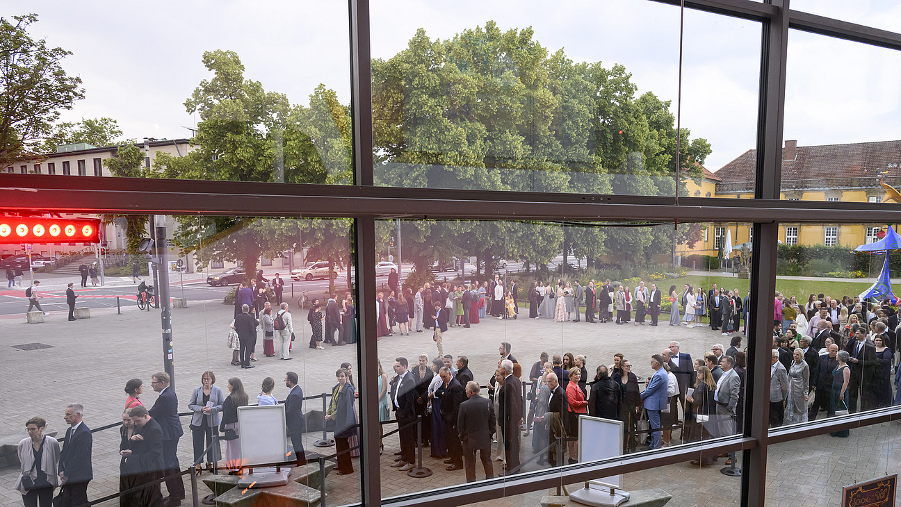 Blick durch die Glasfront der OsnabrückHalle auf die Warteschlange vor dem Eingang