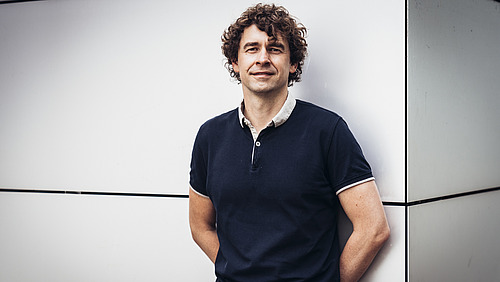 Johannes Krause steht an eine Wand gelehnt.