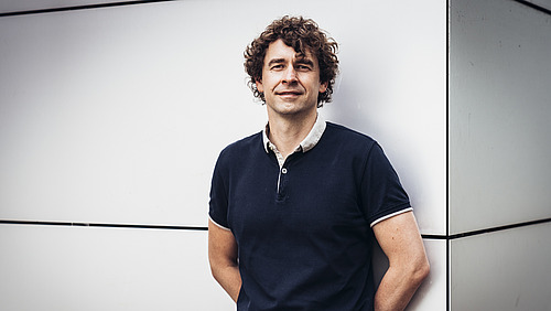 Johannes Krause steht an eine Wand gelehnt.