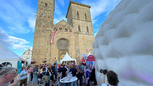 Crowd in front of a historic cathedral with a large inflatable structure in the foreground.