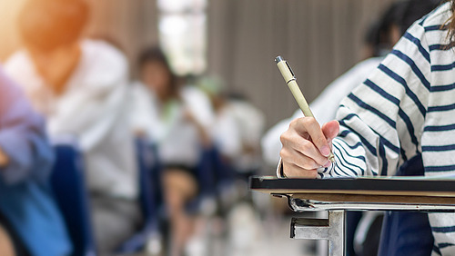 A writing hand in a seminar room or classroom.