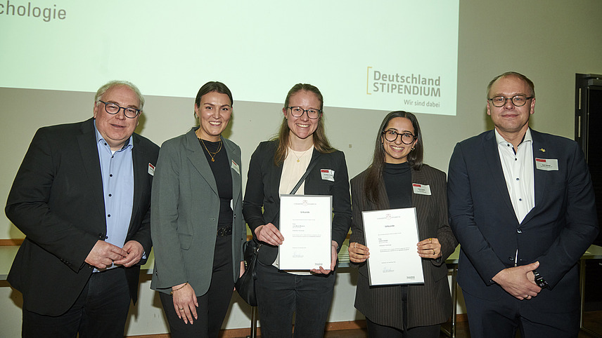 Mehrere Personen auf Bühne bei Urkundenübergabe