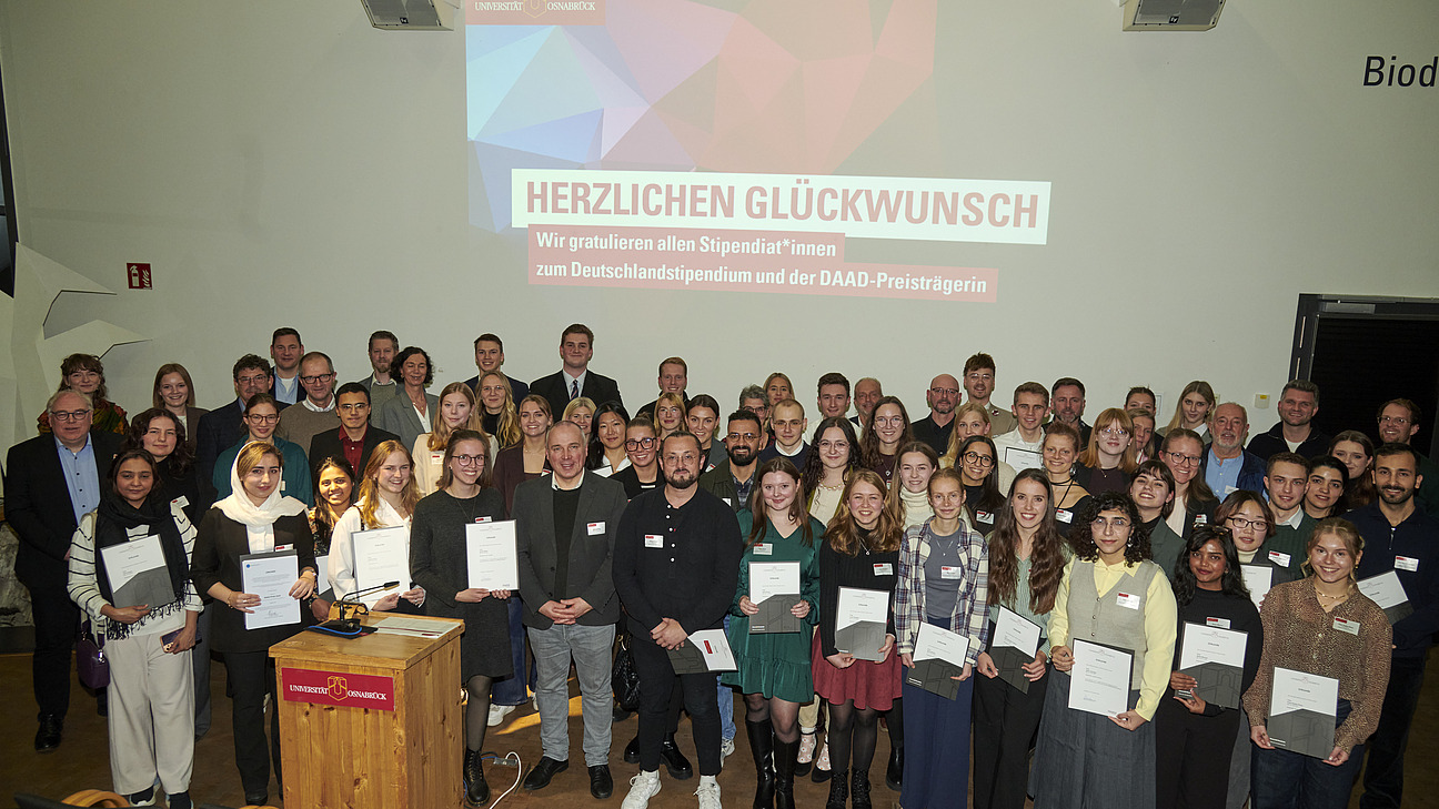 Eine große Gruppe Personen, einige halten Urkunden in den Händen