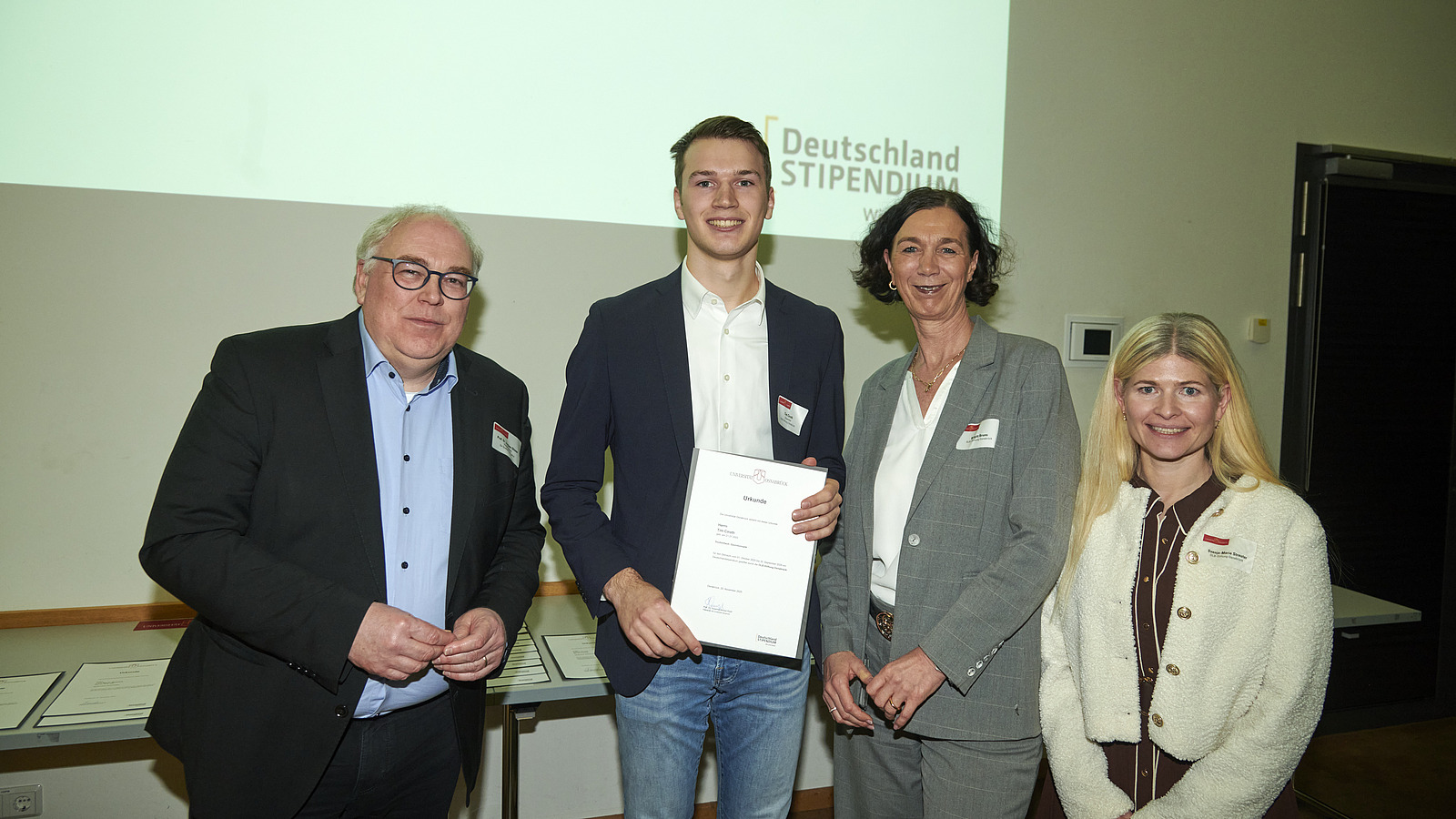 Mehrere Personen auf Bühne bei Urkundenübergabe