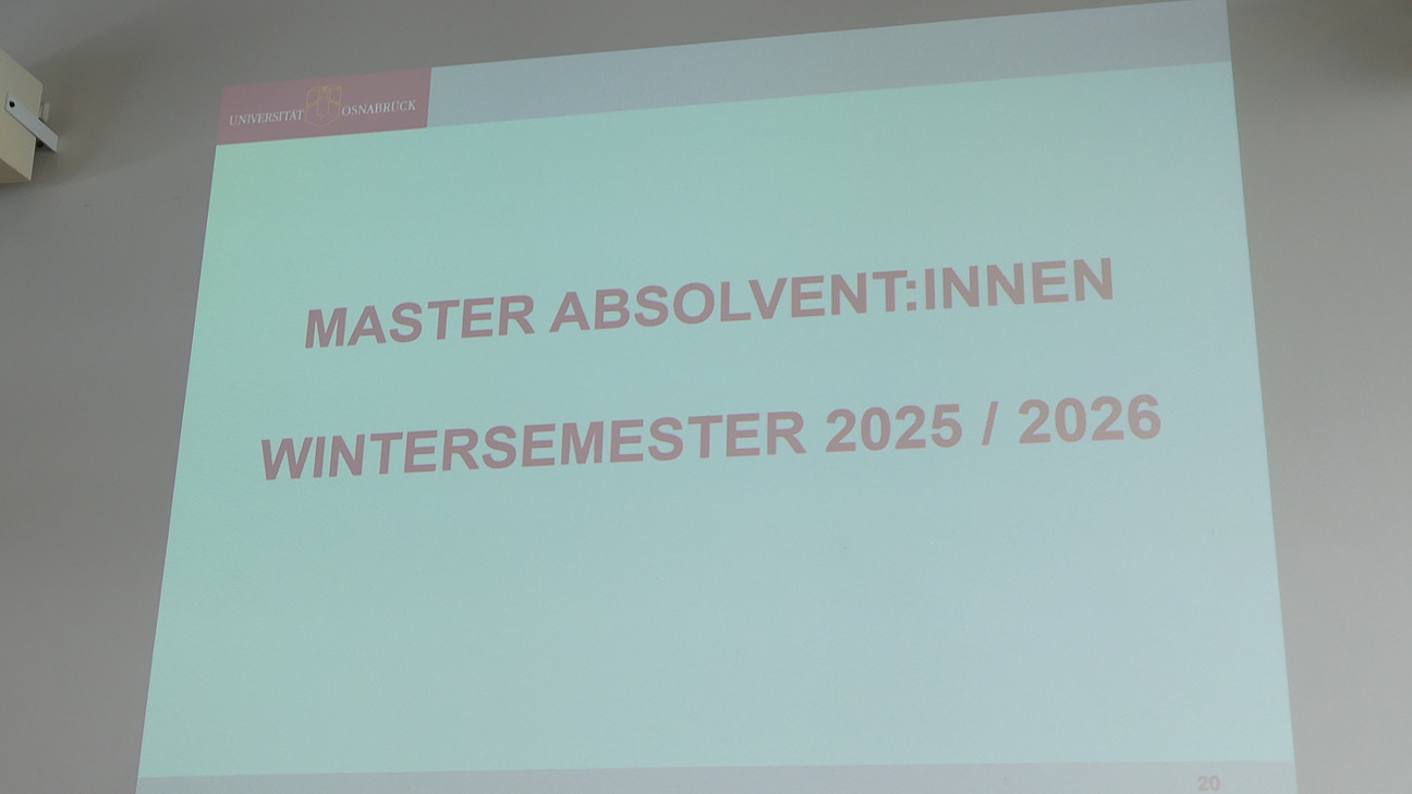 Auf einer Projektion steht: "Masterabsolvent:innen Wintersemester 2025/2026".