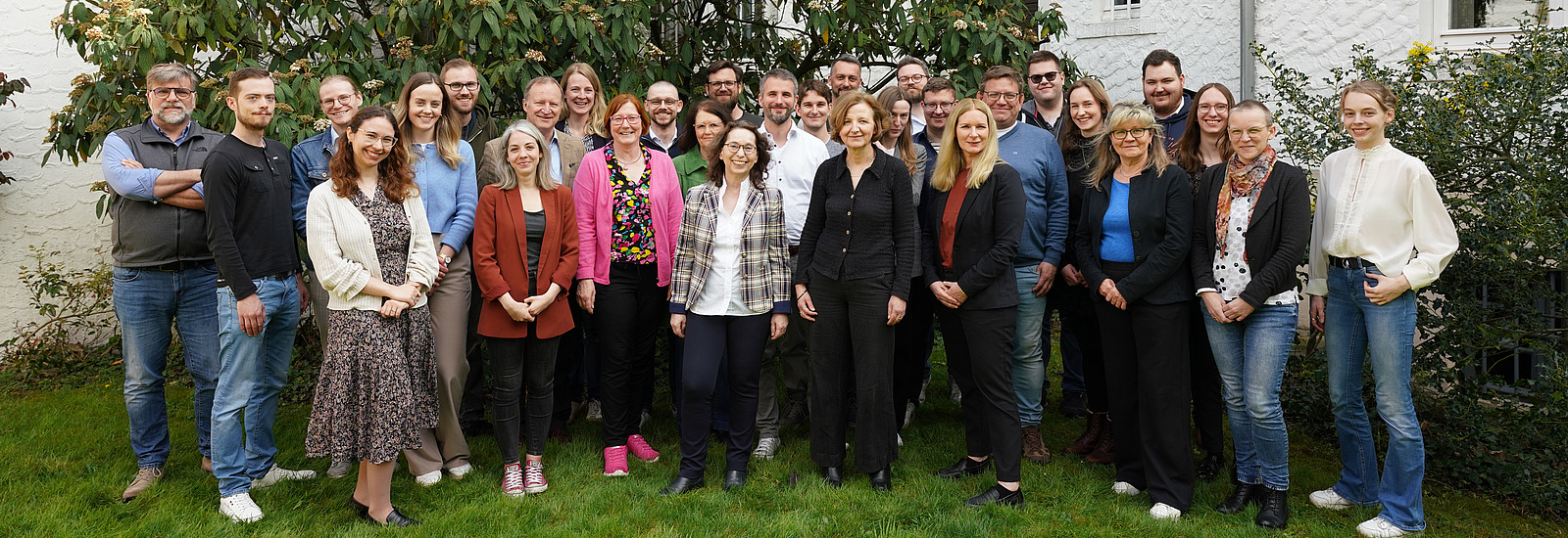Gruppenfoto von etwa 25 Personen vor einem wei&szlig;en Geb&auml;ude. Die Gruppe besteht aus M&auml;nnern und Frauen unterschiedlichen Alters und mit unterschiedlicher Kleidung. Es handelt sich um ein Teamfoto des Historischen Seminars aus dem April 2025..