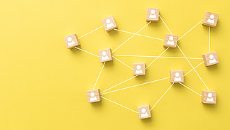 Holzpl&auml;ttchen mit aufgedruckten Icons in Form einer Person sind durch wei&szlig;e Linien verbunden und bilden ein Netzwerk.