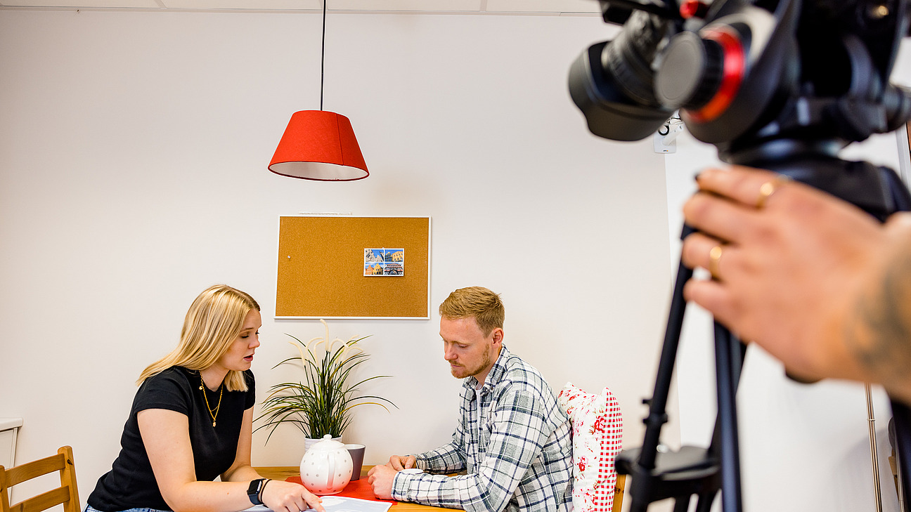 Eine Studierende f&uuml;hrt im Living Lab die Simulation eines Beratungsgespr&auml;chs durch. Diese wird f&uuml;r die sp&auml;tere Auswertung mit einer Videokamera aufgezeichnet.