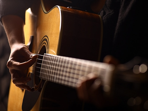 Eine Person spielt Akustikgitarre. 