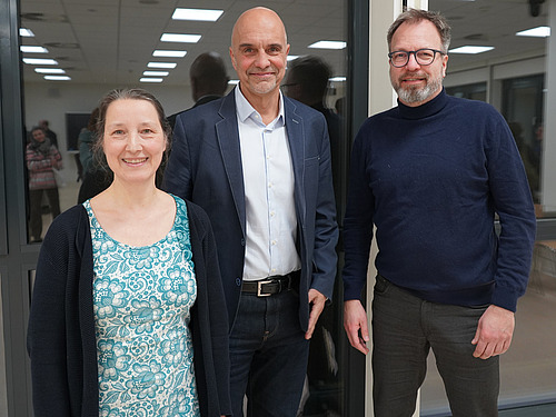 A woman and two men look into the camera.