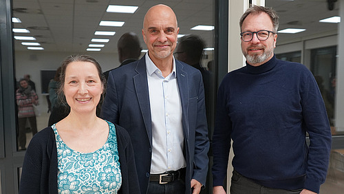 A woman and two men look into the camera.