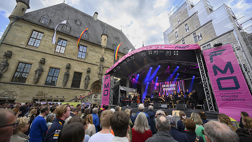 The Osnabrück town hall with a stage in front of it. There are lots of people in front of the stage looking at the musicians on stage.