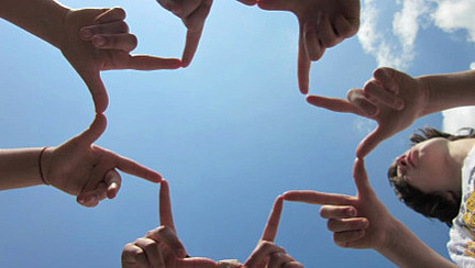 Vier Kinder halten ihre Finger zu einem Kreuz zusammen