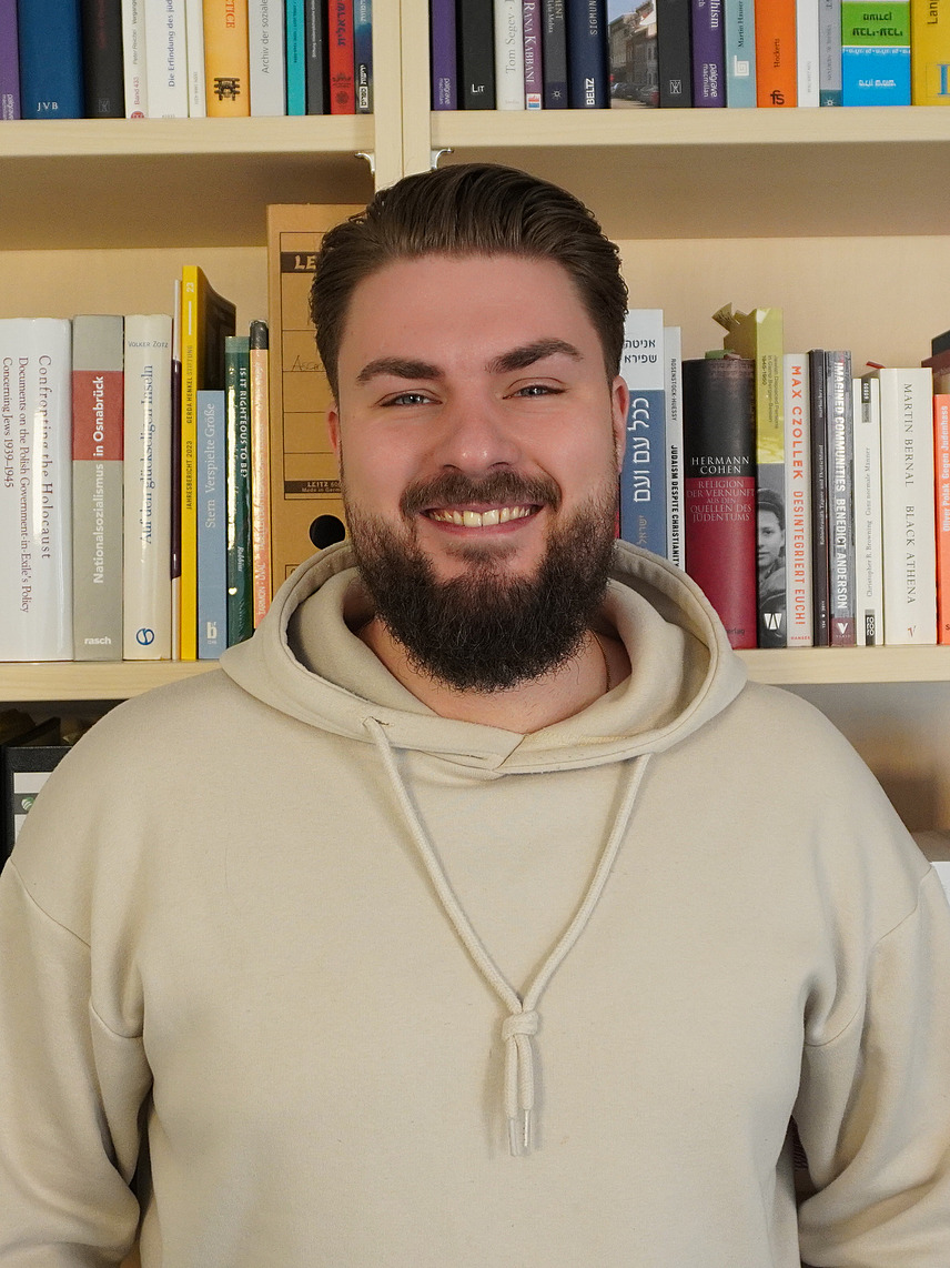 Profilbild von Maik Hoops vor einem Bücherregal