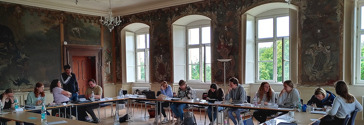 Studierende in einem alten sch&ouml;nen Seminarraum mit hohen Decken und Kronleuchtern