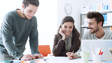 Drei Menschen arbeiten gemeinsam an einem Tisch