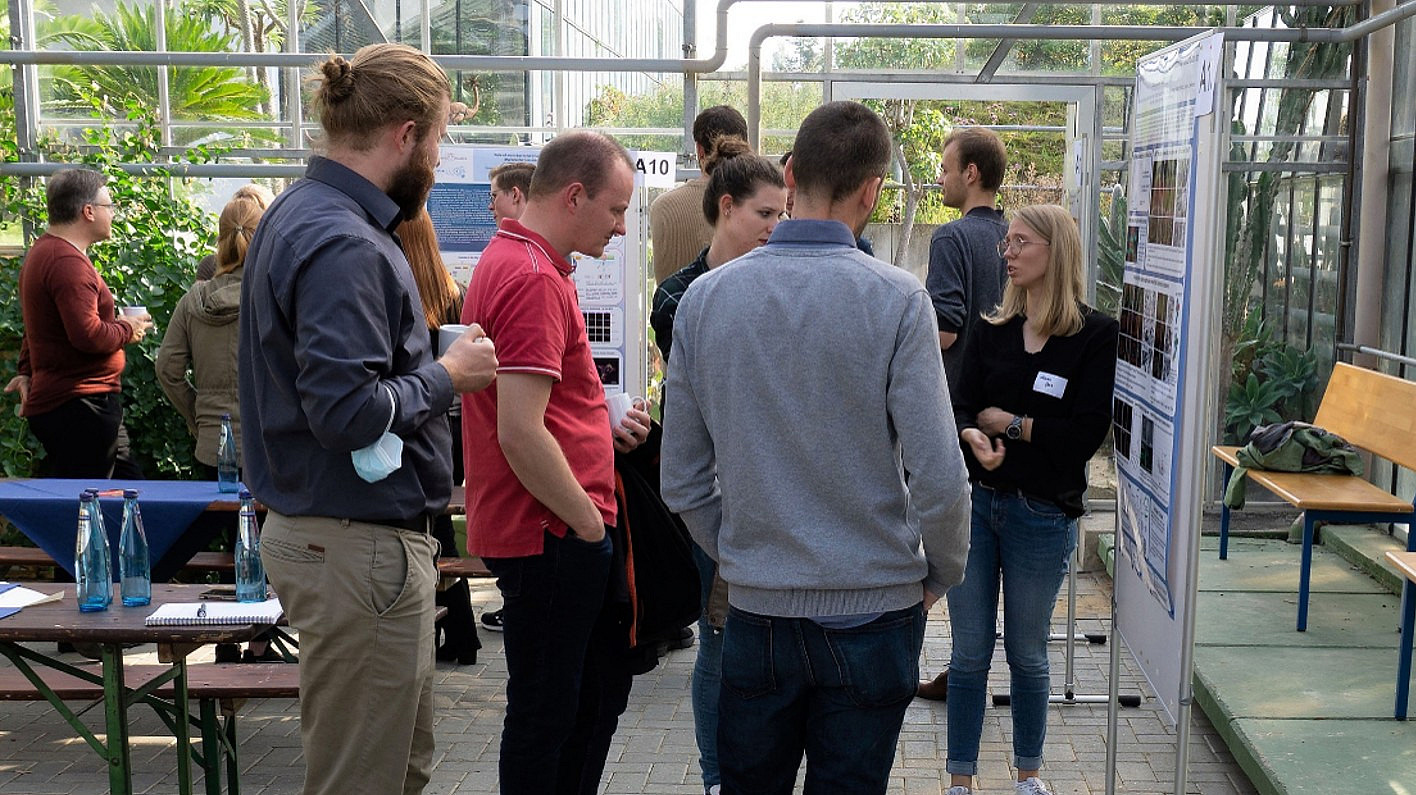Personen stehen vor wissenschaftlichen Postern und diskutieren