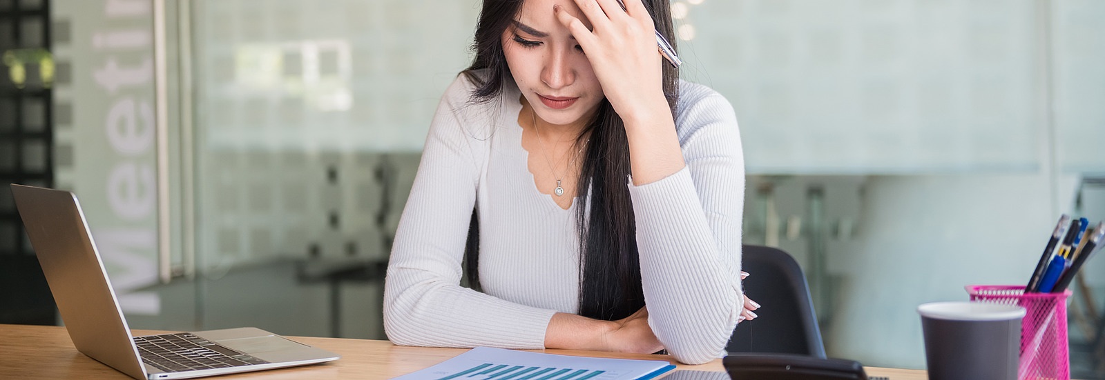 A woman sits at her desk with a serious expression on her face.
