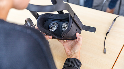 Eine Person hält eine VR Brille in den Händen.