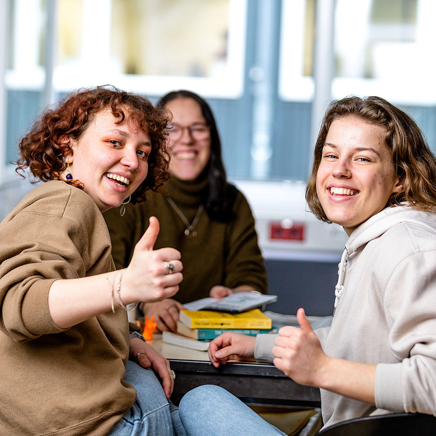 Drei Studierende zeigen den Daumen hoch