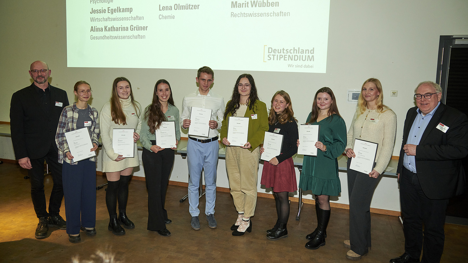 Mehrere Personen auf Bühne bei Urkundenübergabe