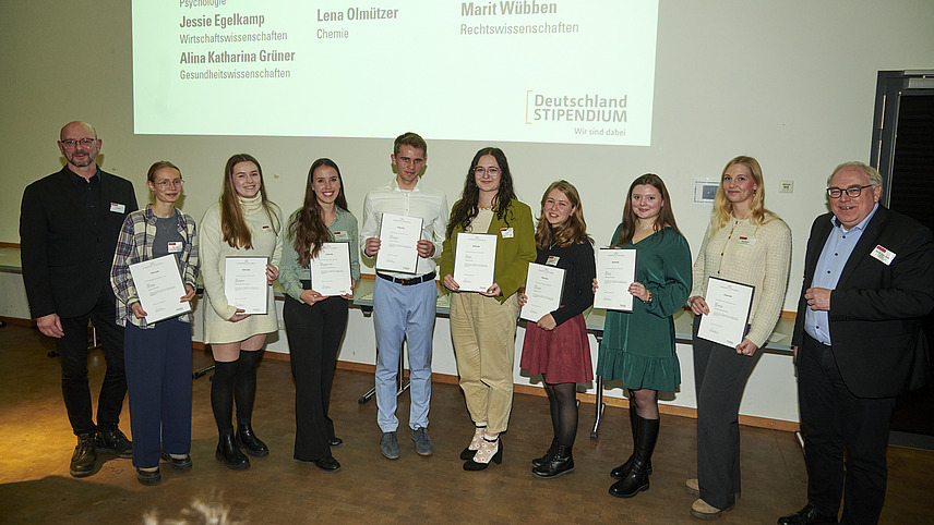 Mehrere Personen auf Bühne bei Urkundenübergabe