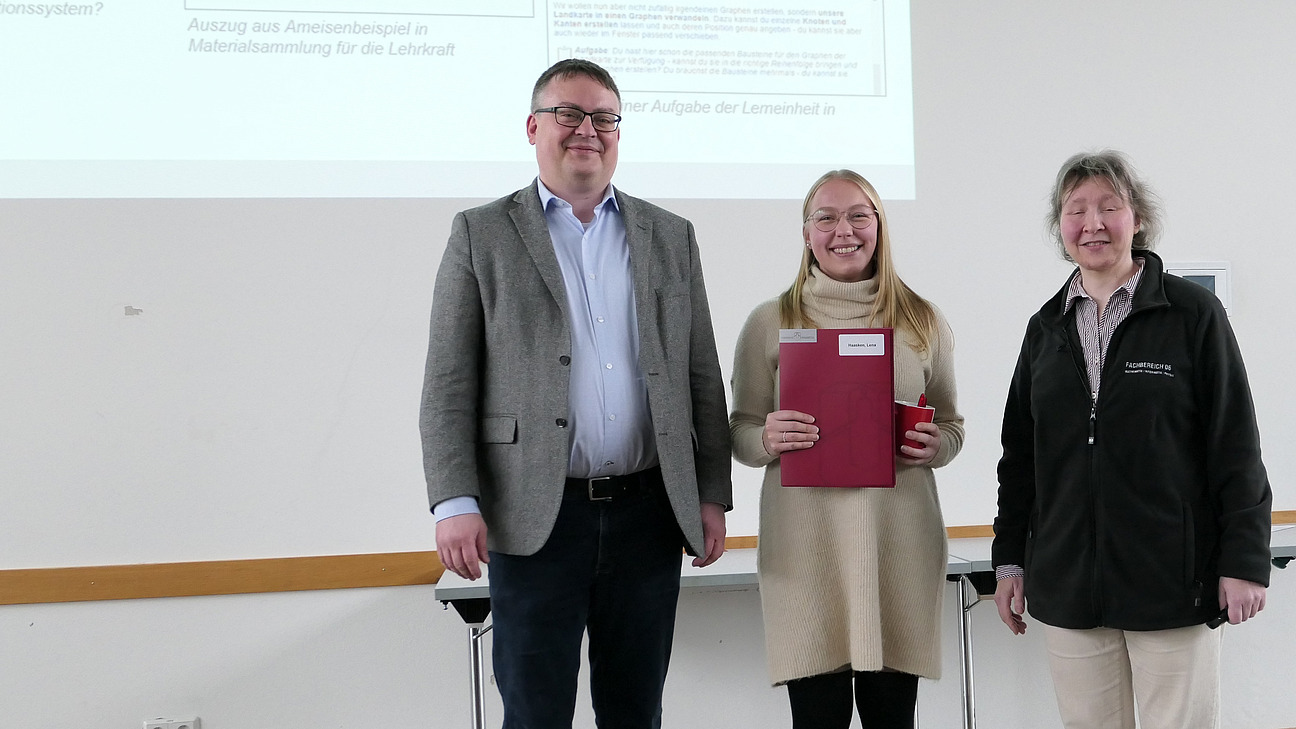 A graduate stands between the dean and the dean of studies.