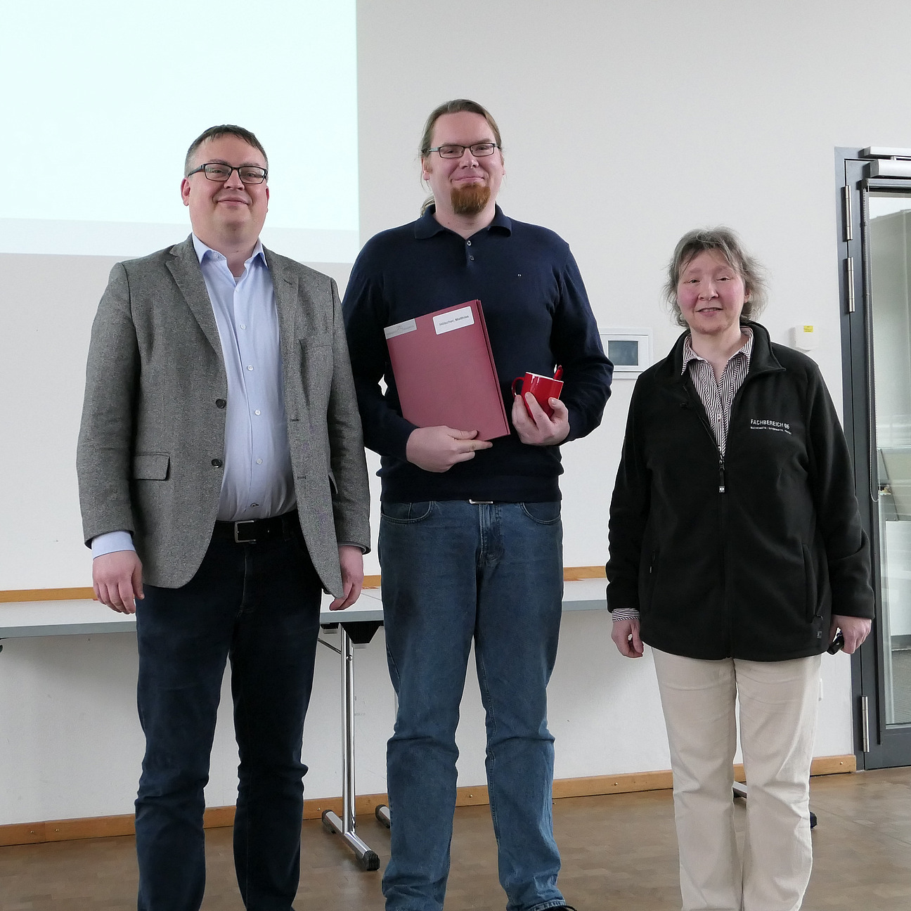 A graduate stands between the dean and the dean of studies.