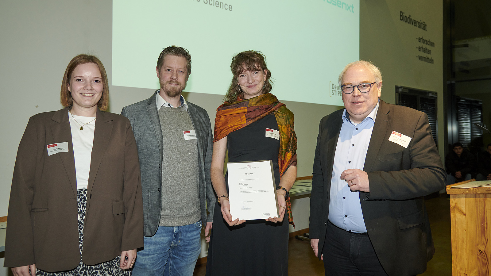 Mehrere Personen auf Bühne bei Urkundenübergabe