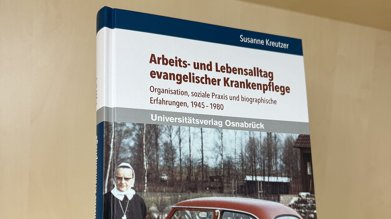 Ein Fachbuch von Susanne Kreutzer mit dem Titel "Arbeits und Lebensalltag evangelischer Krankenpfleger. Organisation, soziale Praxis und biographische Erfahrungen, 1945-1980" steht in einem Regal.