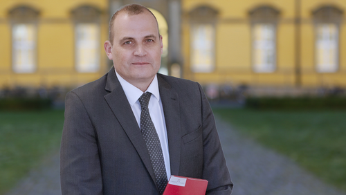 Prof. Skudlik mit Ernennungsurkunde, im Hintergrund sieht man das Osnabr&uuml;cker Schloss