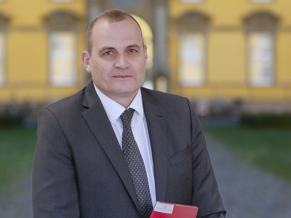 Prof. Skudlik mit Ernennungsurkunde, im Hintergrund sieht man das Osnabr&uuml;cker Schloss