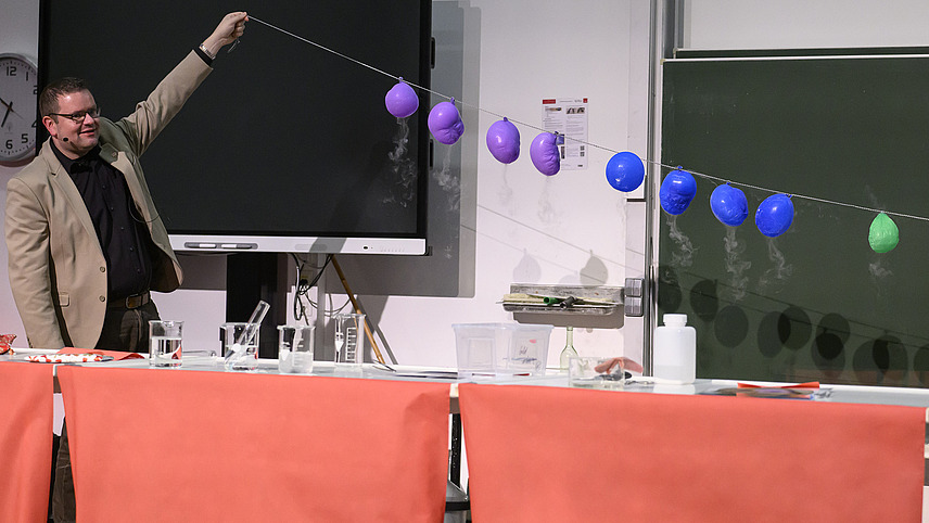 Ein Mann unternimmt ein chemisches Experiment mit Hilfe von Luftballons