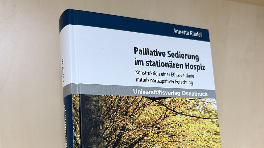 Ein Fachbuch von Annette Riedl mit dem Titel "Palliative Sedierung im station&auml;ren Hospiz. Konstruktion einer Ethik-Leitlinie mittels partizipativer Forschung" steht in einem Regal.