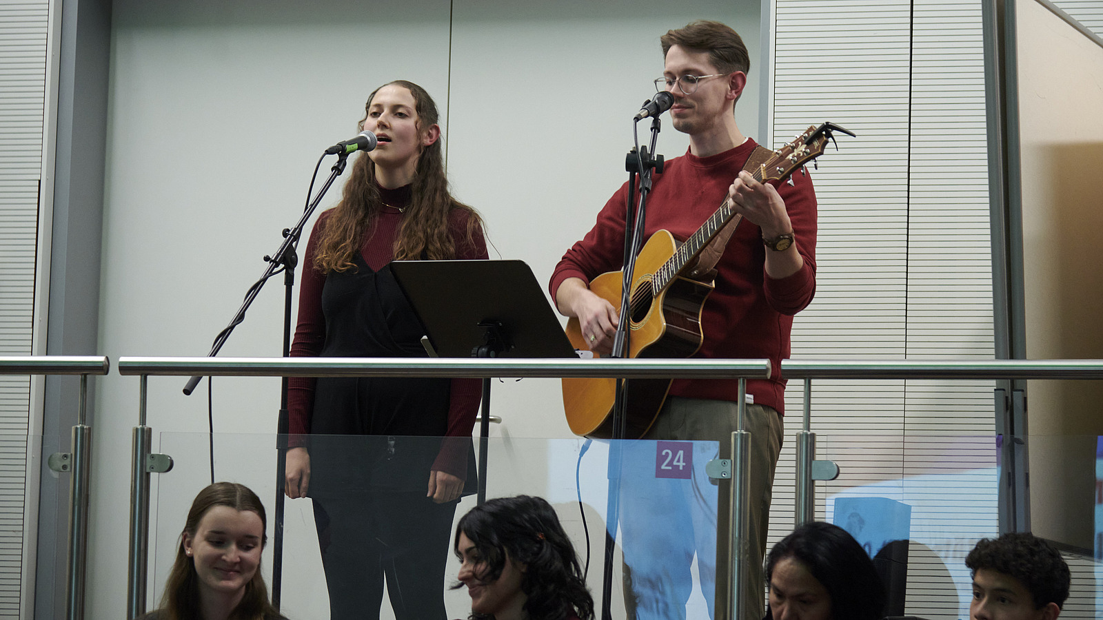 Eine singende Frau neben einem Mann mit Gitarre