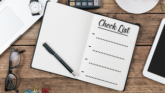 Ein Buch mit einer Strichliste auf einem Schreibtisch. Es liegt ein Kugelschreiber auf dem Buch und weitere Gegenst&auml;nde sind drumherum verteilt.