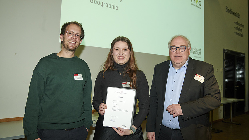 Mehrere Personen auf Bühne bei Urkundenübergabe