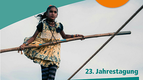 Ein Mädchen in einem bunten Kleid balanciert auf einem Seil